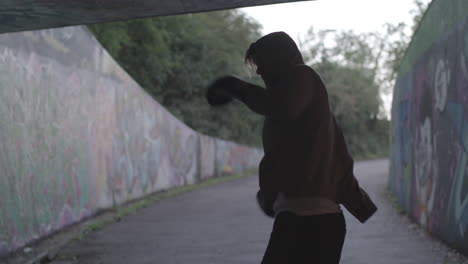 wide shot of young attract man boxing in underpass, in slow motion