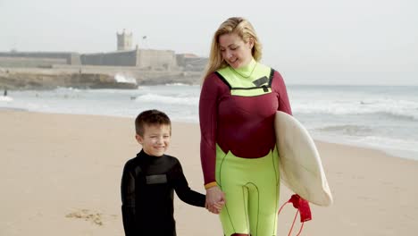 Surferin-Mit-Kleinem-Sohn,-Die-Am-Strand-Spaziert