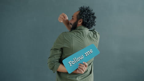man holding up a 'follow me' sign