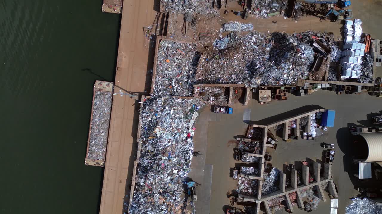 metal scrap yard, showing workers sorting and managing waste materials for recycling purposes near a city. Best aerial view flight vertical bird's eye view drone