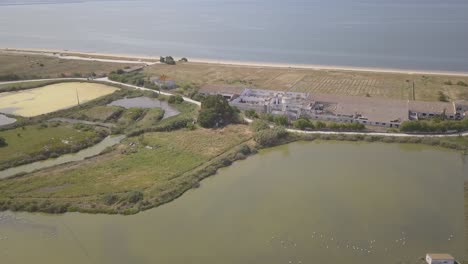 Aerial,-orbit,-Drone-Shot-Tilting-Towards-A-historic-ruins,-Surrounded-By-shallow-water-pools,-on-a-sunny-day,-in-Montijo,-Portugal