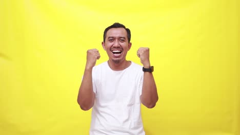 happy asian adult man standing while clenching hands