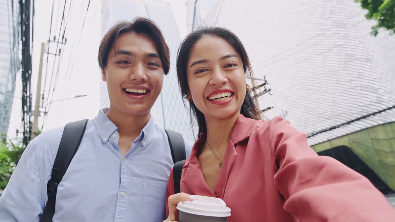 Two Smiling Young Adults Taking a Selfie with Coffee on a City Street