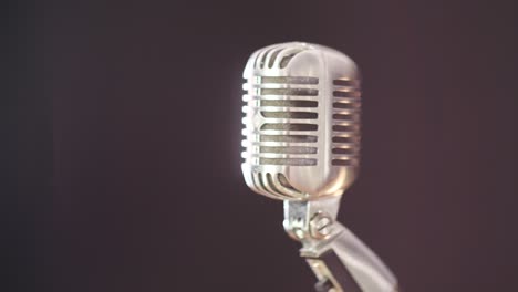 a vintage elvis microphone in front of a dark background with a light source out of frame