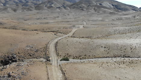 road crossing arid desert of morocco with mountains in background