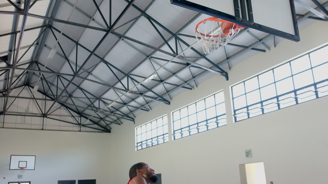 hombre afroamericano jugando al baloncesto en el interior, con espacio de copia