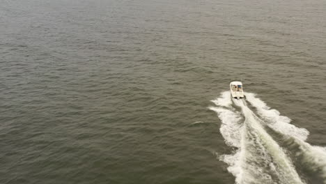 an aerial view of a small, white fishing boat speeding in the deep, green atlantic ocean near long island, ny