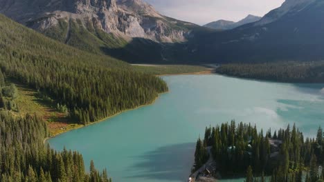 aerial rising over emerald lake louise between pine woods and canadian rockies at banff national park, alberta, canada