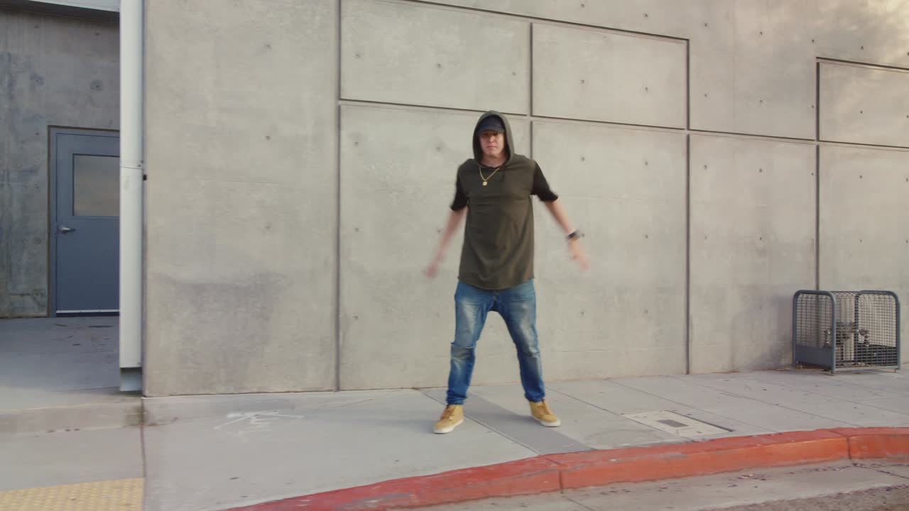 Uomo che balla hip hop freestyle lungo il marciapiede cittadino