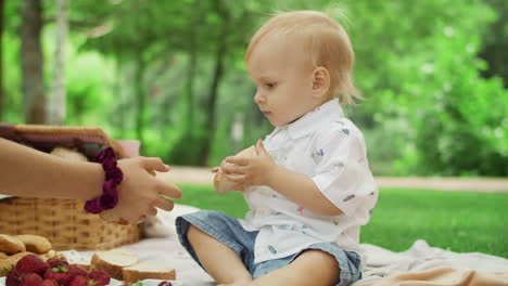 three kids sitting on blanket in park. portrait of happy toddler eating bread