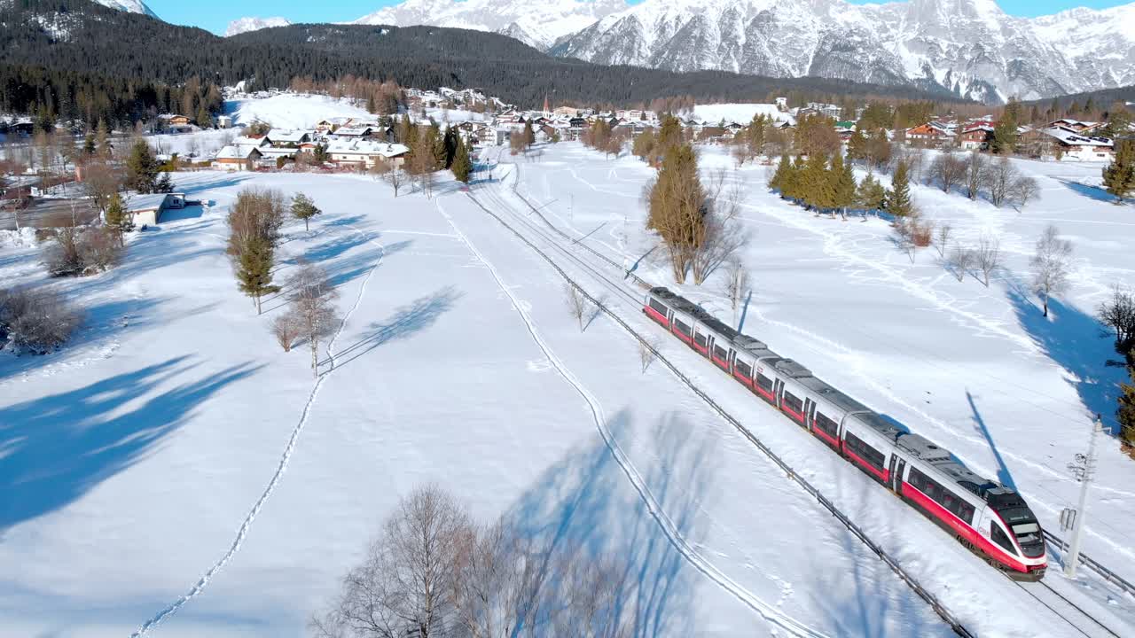 Aerial: Passenger train crossing a winter landscape in Seefeld in Tirol, Austria