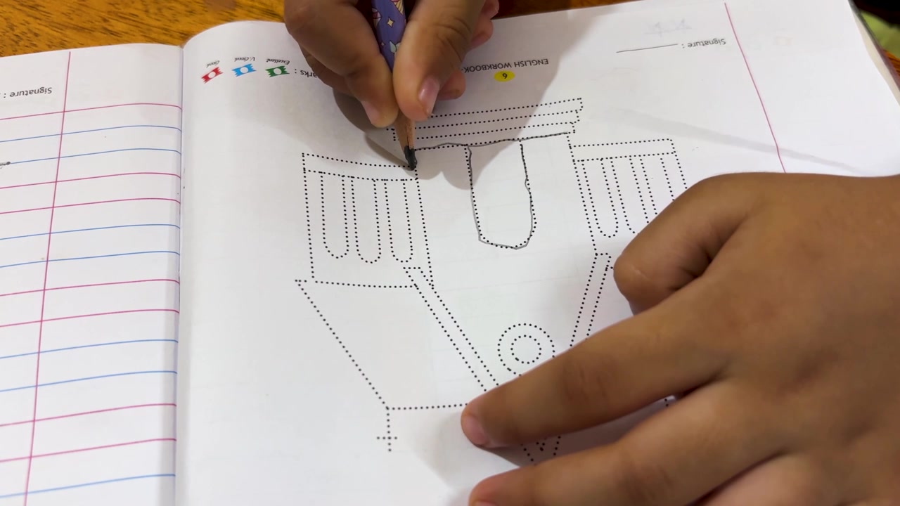 Young Child Learning To Trace Shapes With Pencil In Workbook