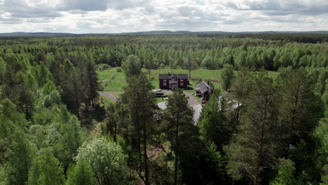 sunny drone view of swedish red farm houses forest and lake landscape, backing up