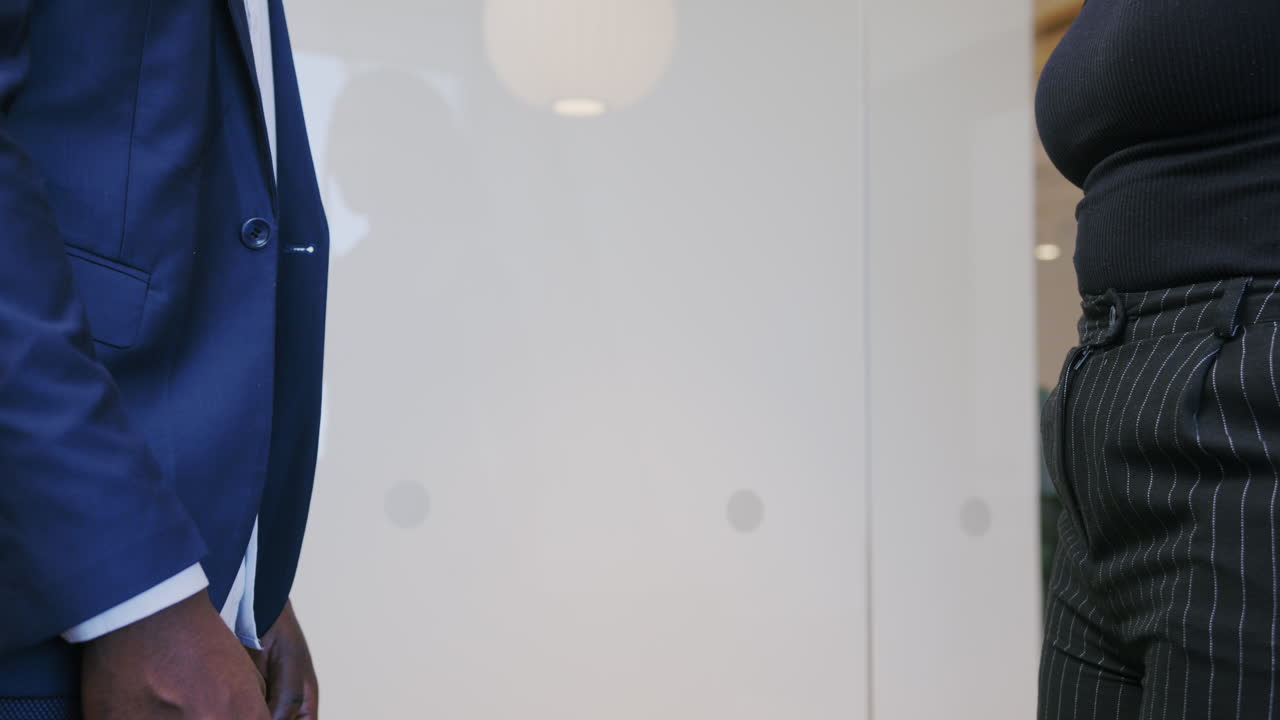 African man and woman shaking hands in a corporate setting, symbolizing collaboration, professionalism, and successful teamwork