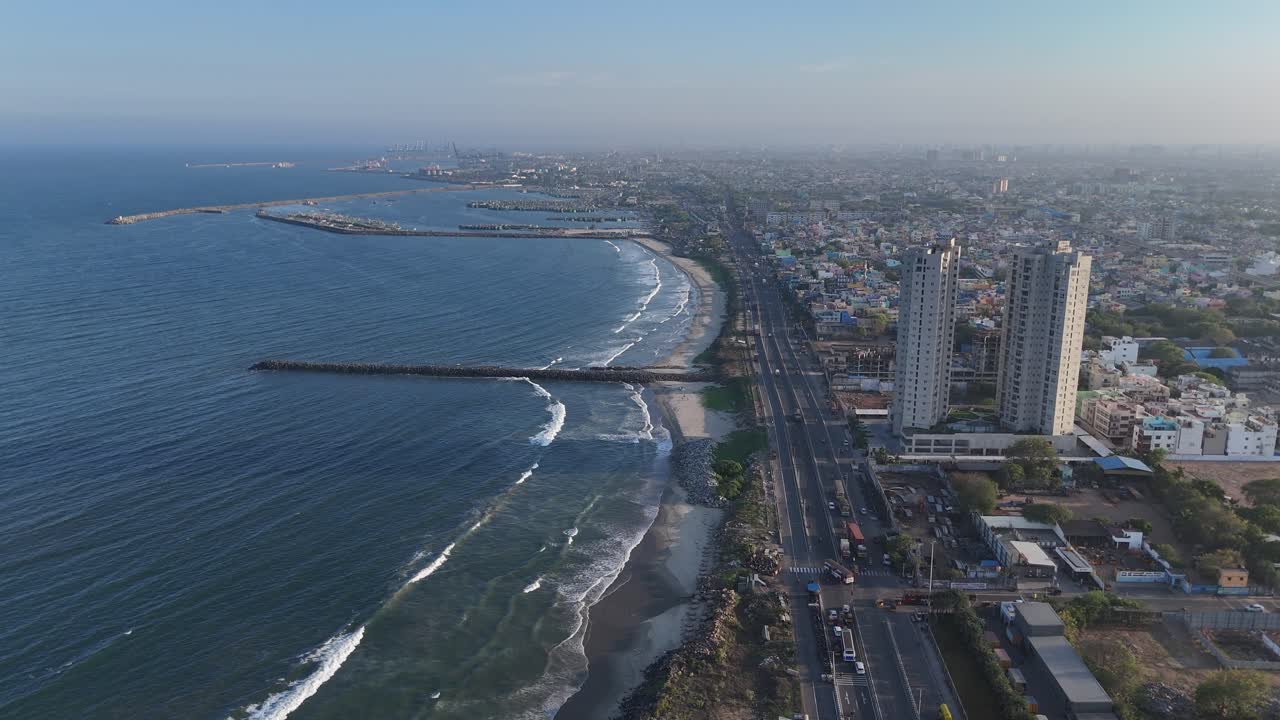 Drone shot of a coastal city showing residential zones, fishing activities, and urban infrastructure merging with the ocean
