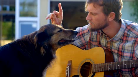 man with his dog playing guitar in the garden 4k