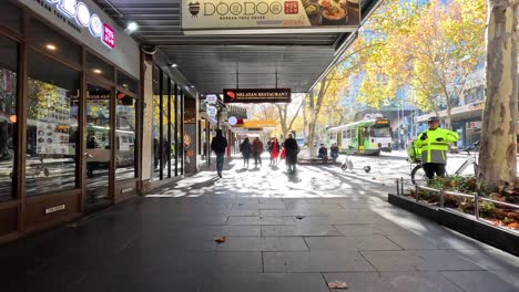 people walking along a sunny city street