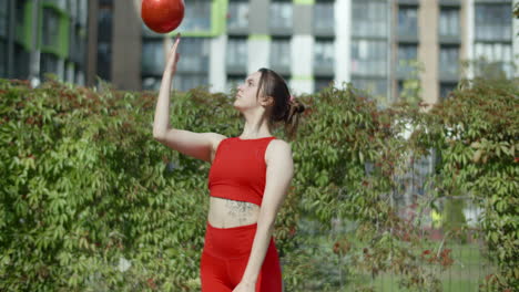 woman juggling a red ball in an urban setting