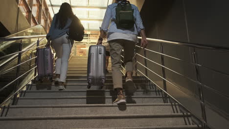 travelers climbing stairs with luggage at night