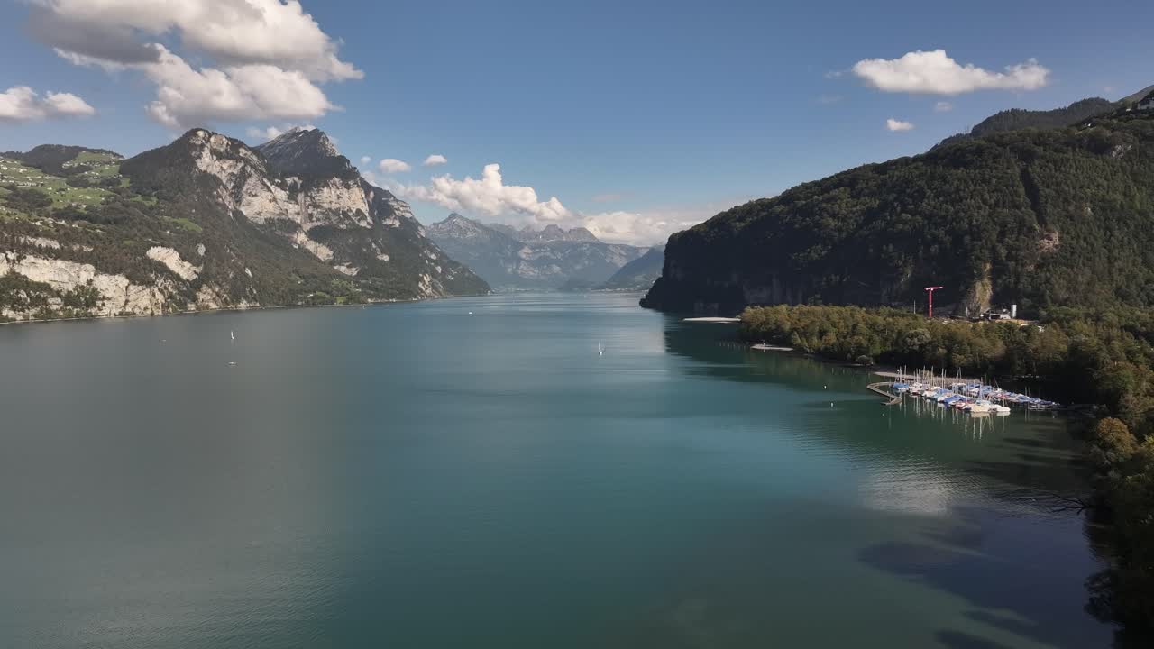 Village of Wessen with moored boats on Lake Walensee. Amazing natural scenery in the mountains of Switzerland. Aerial view
