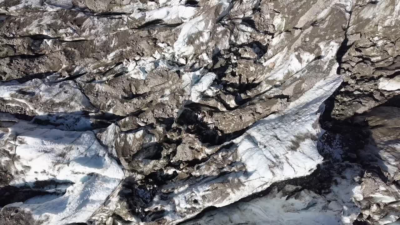 vista aérea de arriba hacia abajo de grietas de glaciares sucios en los alpes suizos