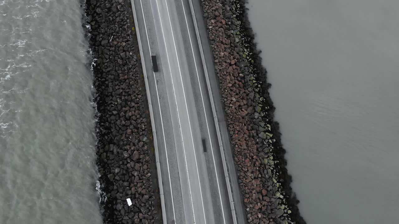 foto aérea de una carretera y un puente vacíos rodeados por el mar en islandia