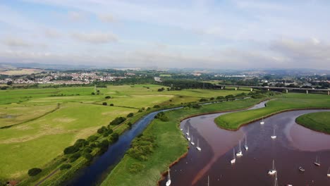 Antenne-über-Segelbooten,-Die-Im-Fluss-Exe-In-Topsham-Verankert-Sind,-Schwenk-Nach-Links-Zu-Grünen-Feldern