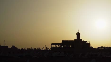 silhouette of buildings in moroccan desert during bright yellow sunset, slowmo