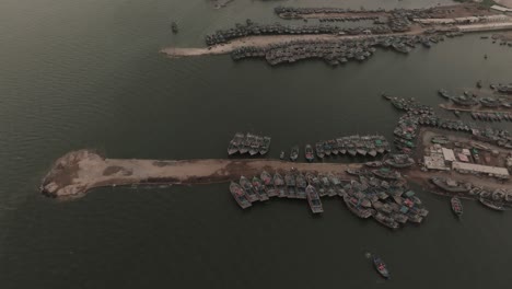 Aerial-View-Of-Fishing-Boats-Moored-Along-Marina-At-Ibrahim-Hyderi-In-Karachi