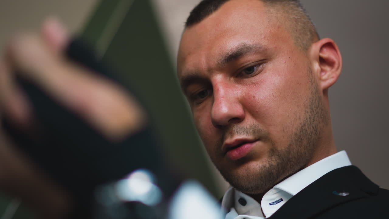 hombre concentrado en traje negro con camisa mira hacia abajo en la habitación