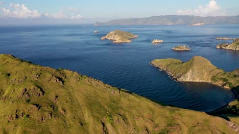 padar island southern tip with komodo isle in the distance in indonesia, aerial pan right reveal shot