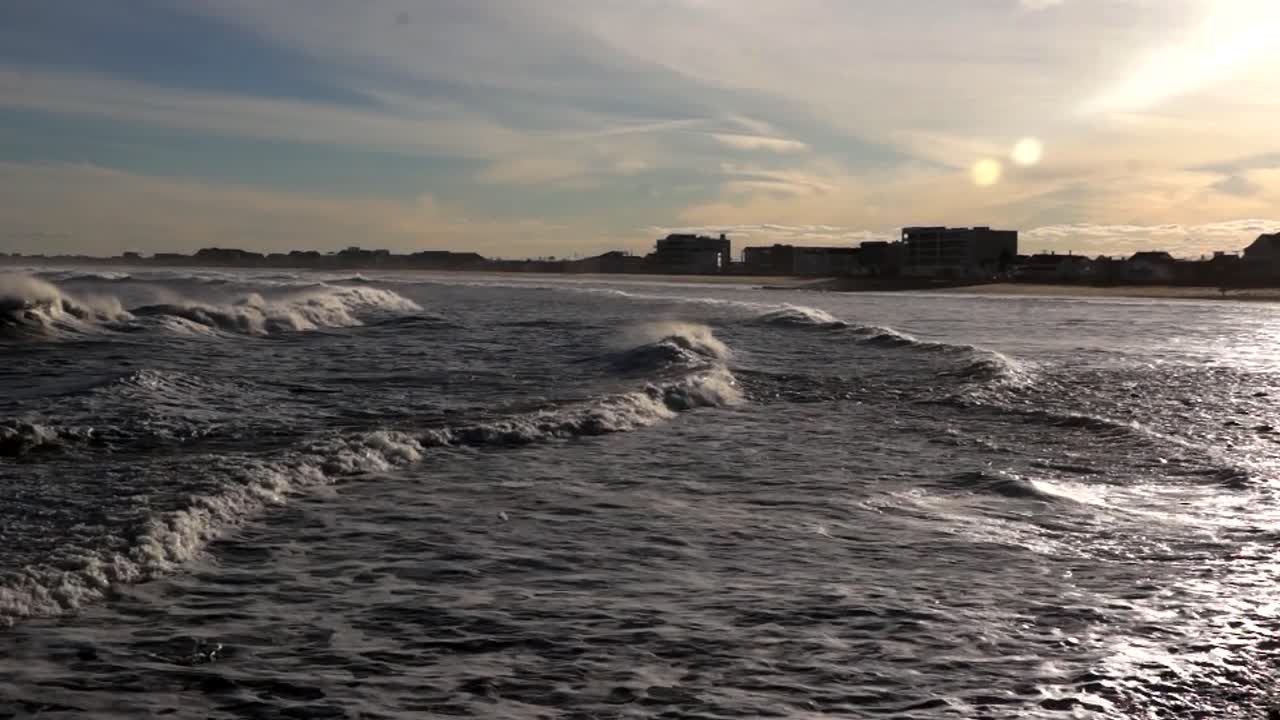 뉴 햄프셔주 햄튼 해변 위로 해가 지면 파도가 매혹적인 움직임을 보입니다.