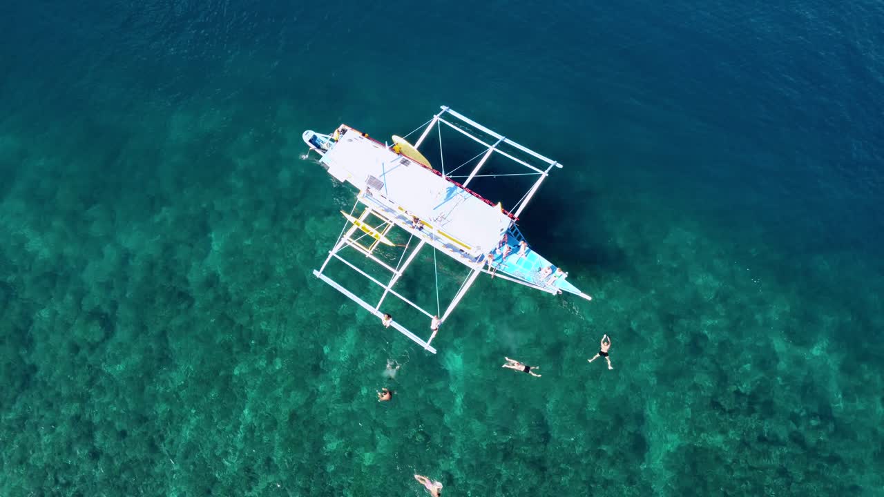 항공, 젊은 관광객 그룹이 섬에서 재미를 즐기고 엘 니도에서 보트에서 뛰어내려 크리스탈  ⁇ 은 열대 물에서 수영하고 있습니다.