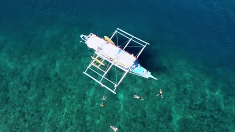 Aerial,-young-Tourists-Group-having-fun-on-island-hopping-tour-in-El-Nido-jumping-off-Boat-and-swimming-in-Crystal-Clear-tropical-water