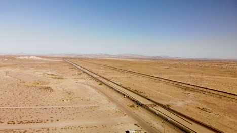 aerial view of a long straight highway stretching through a barren dessert on a sunny day