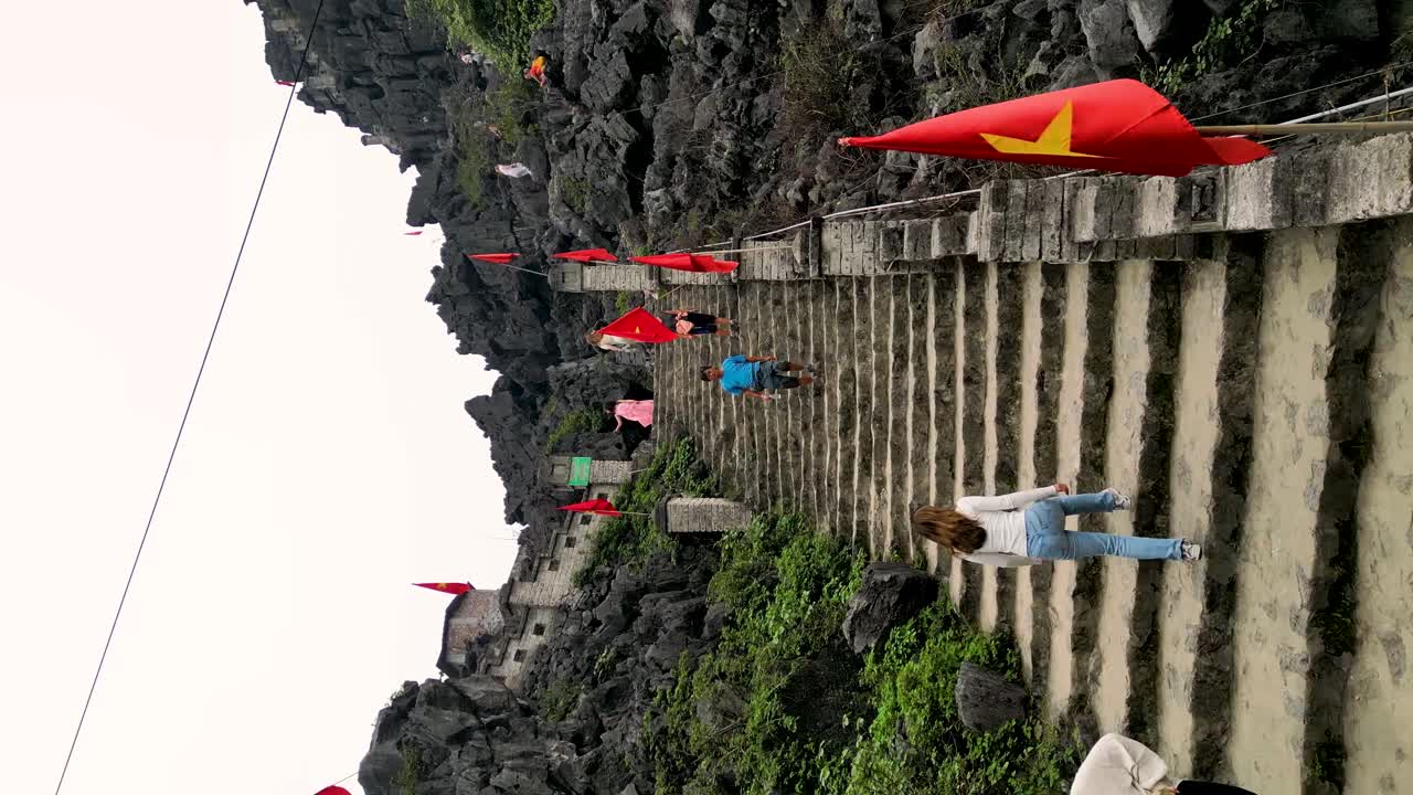 vertical aerial shot of tourists climbing to the Hang Mua mountain viewpoint