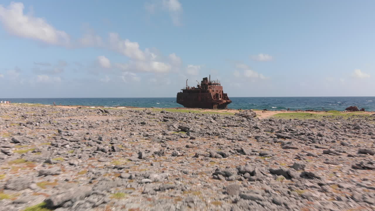 Klein Curaçao’s shipwreck rests on the reef edge, waves foaming around rusted steel. — island view