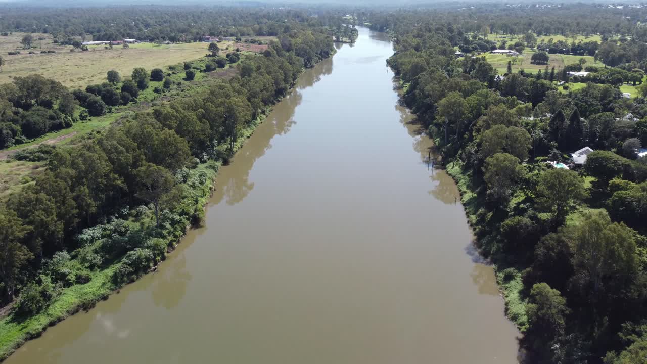 4K Drone shot of a small brown river lined with lush green vegetation in Australia
