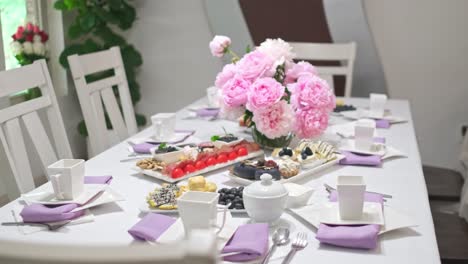 a fancy tea set up with pink flower centerpiece and elegant desserts laid out on a table