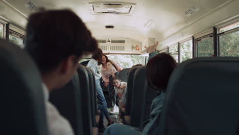 High-school-students-sitting-communicating-in-schoolbus.-Pupils-waving-friend.