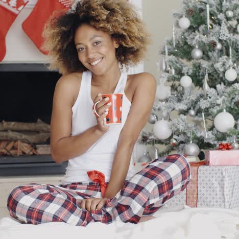 mujer joven sonriente disfrutando de una taza de café de navidad