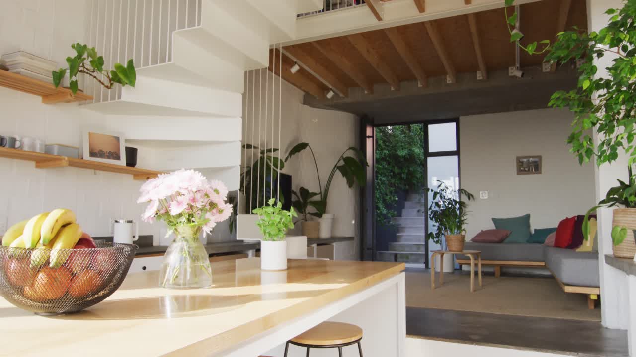 General view of modern kitchen and living room with countertop, sofa and staircase