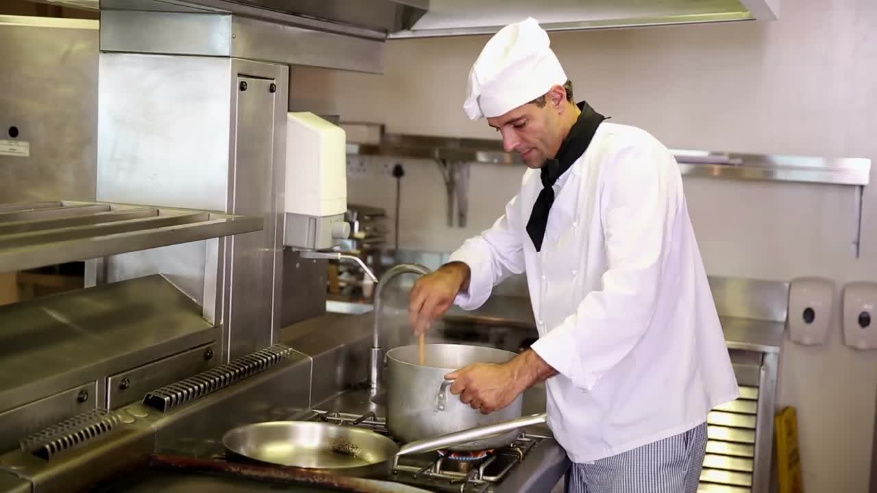 Bello chef che mescola una grande pentola