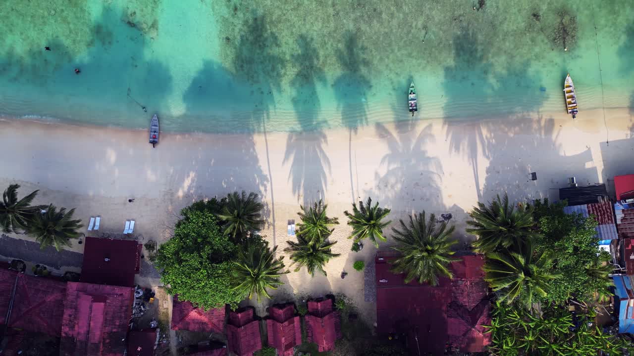 Tourists enjoying the tropical paradise with a resort nestled among palm shade and lush vegetation on the coast of a tropical island