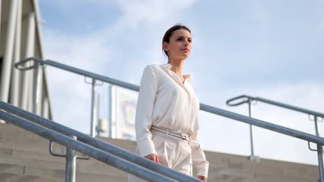 A-businesswoman-stands-on-a-staircase-and-looks-around-medium-shot