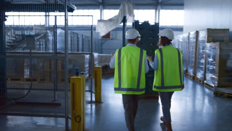 dos trabajadores de almacén investigando el complejo de la fábrica de logística discutiendo la producción