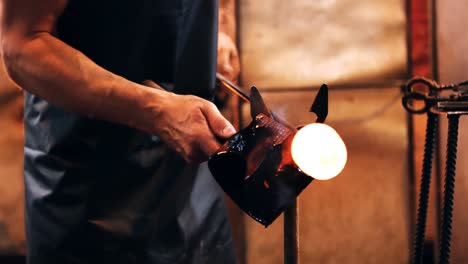 mid section of glassblower forming and shaping a molten glass