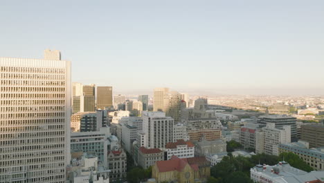 Fly-above-buildings-in-city-centre-lit-by-bright-sunshine.-Long-straight-streets-and-multistorey-office-or-apartment-structures.-Cape-Town,-South-Africa