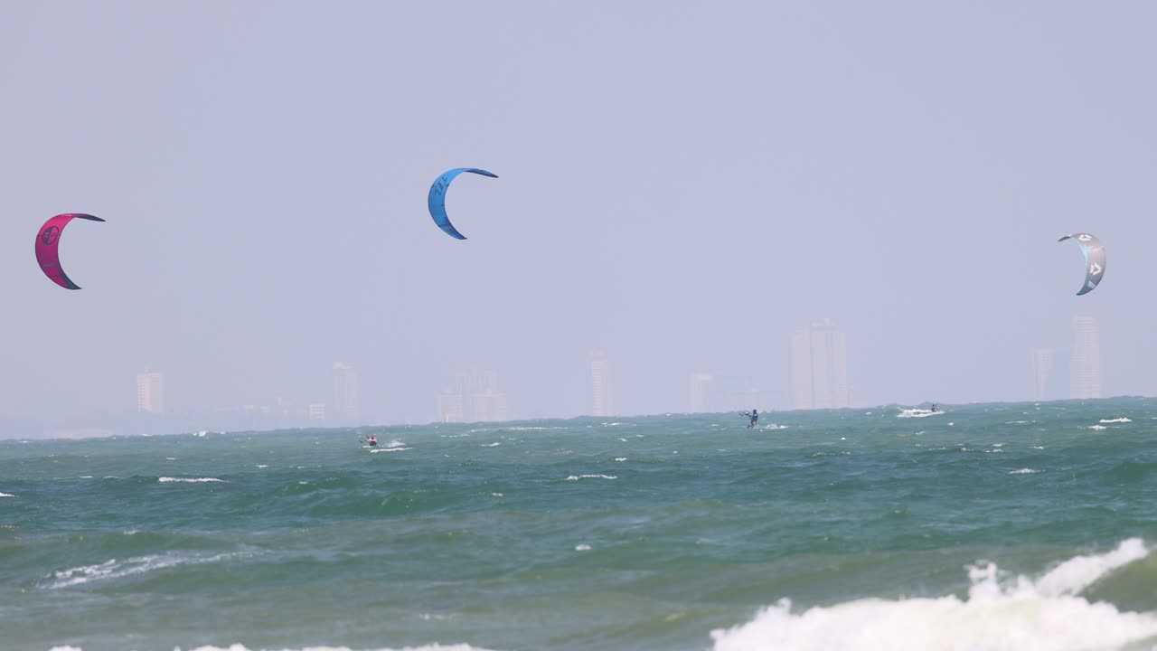 카이트 서퍼 들 은 바다 의 흔들리는 파도 를 가로질러 미끄러진다