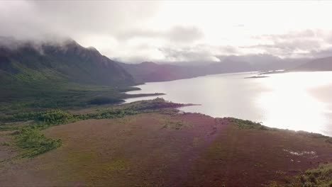 Aerial-flight-over-foggy-mountains-and-reflective-lake-Tasmania-in-Australia,-long-distance-shot-moving-forward